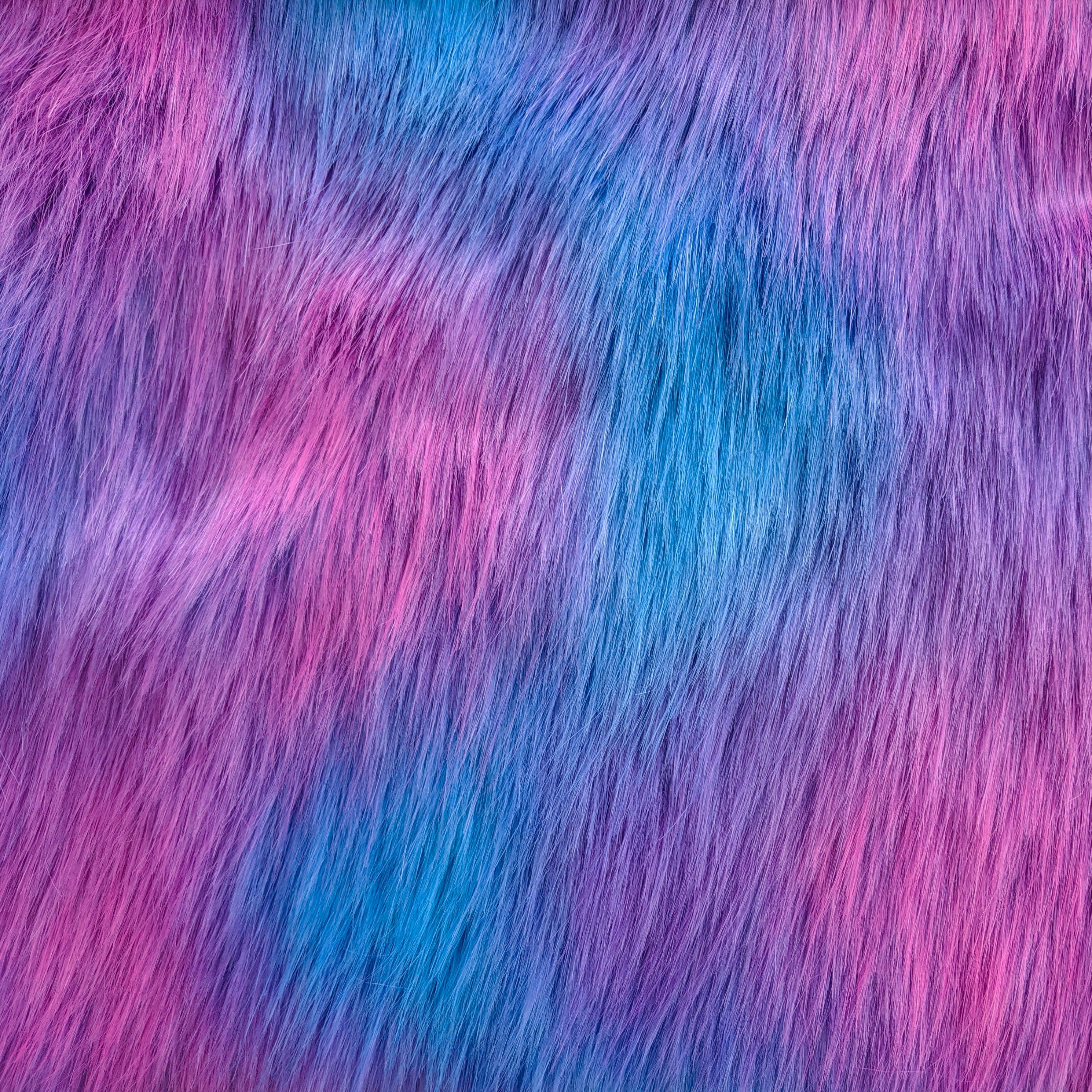 Long pile dreamsicle faux fur fabric laid flat. Dreamsicle has a light blue base with purple and pink streaks  throughout.
