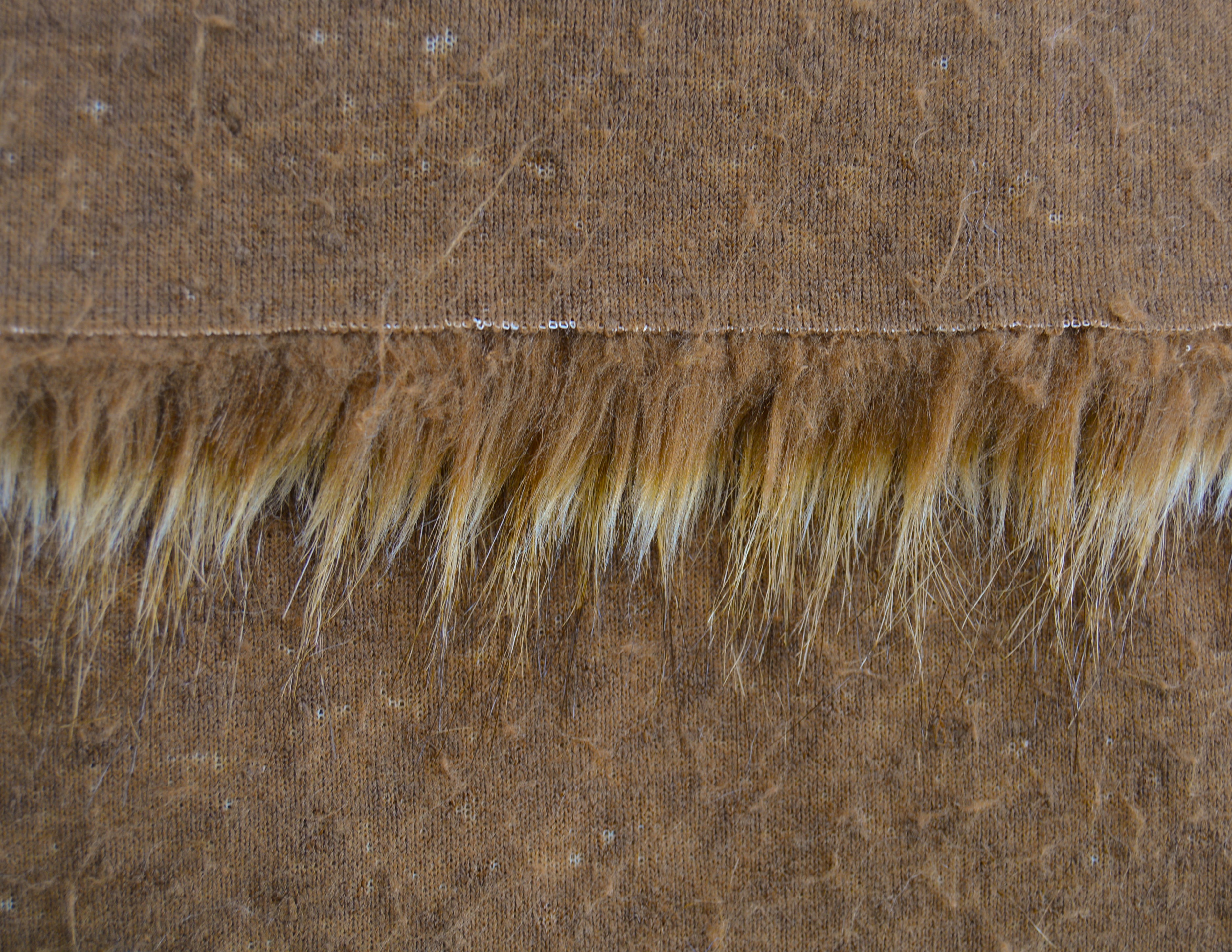 Backing of grizzly brown faux fur fabric showing the long pile length of the fake fur.