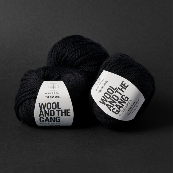 Two black yarn balls with 'Wool and the Gang' labels on a dark background