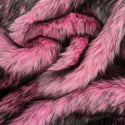Flamingo pink faux fur fabric with folds.  A pink long pile fake fur fabric.