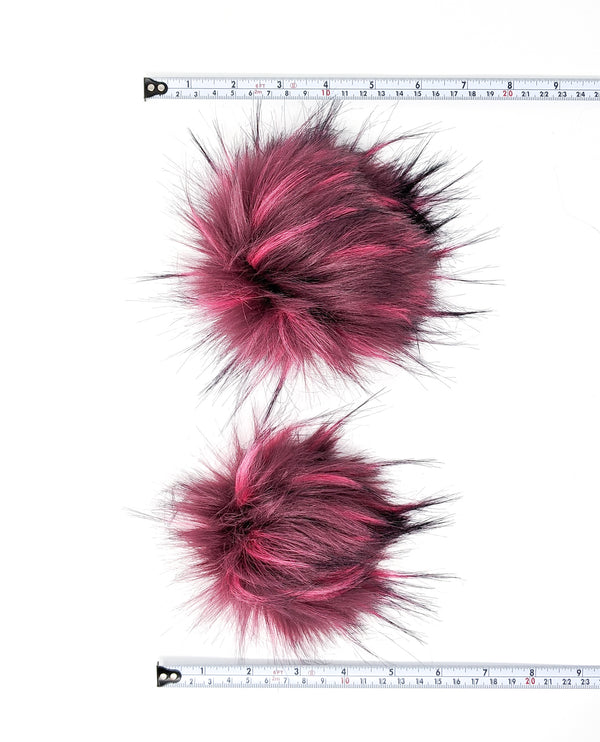 Raspberry faux fur pom poms with measuring tapes.