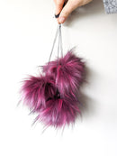 Raspberry faux fur pom poms held by strings.