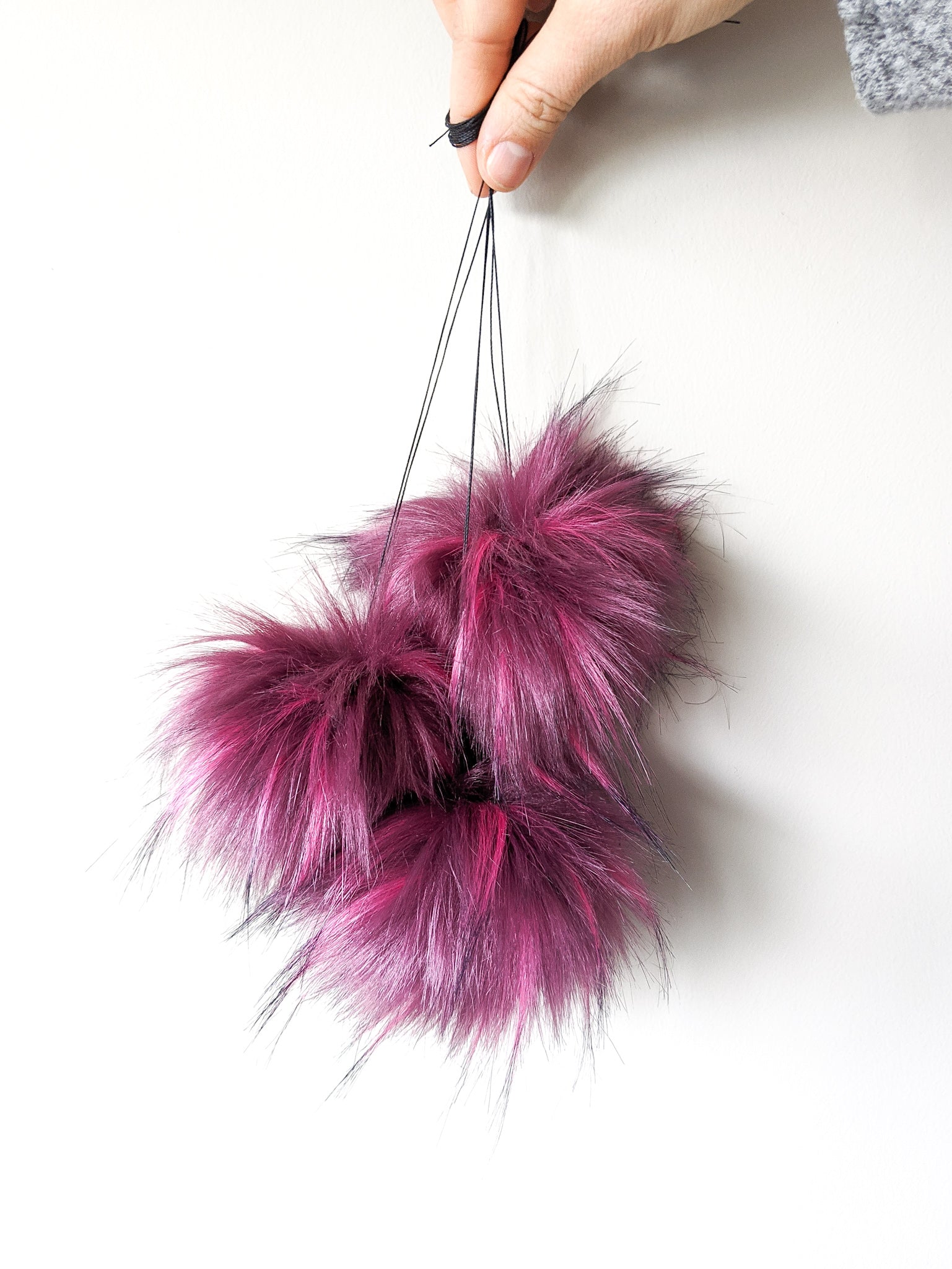 Raspberry faux fur pom poms held by strings.