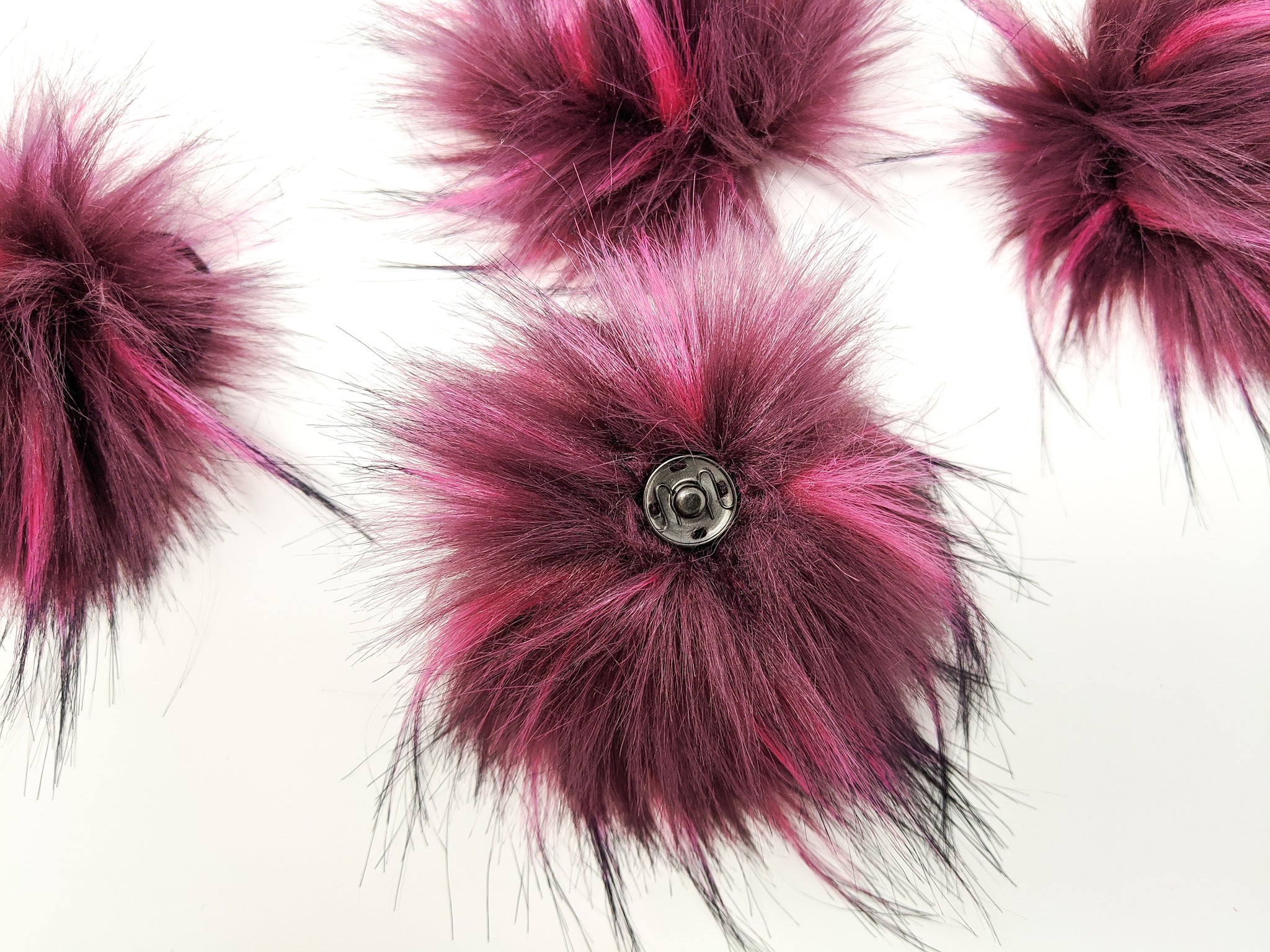 Raspberry faux fur pom pom with a metal snap.