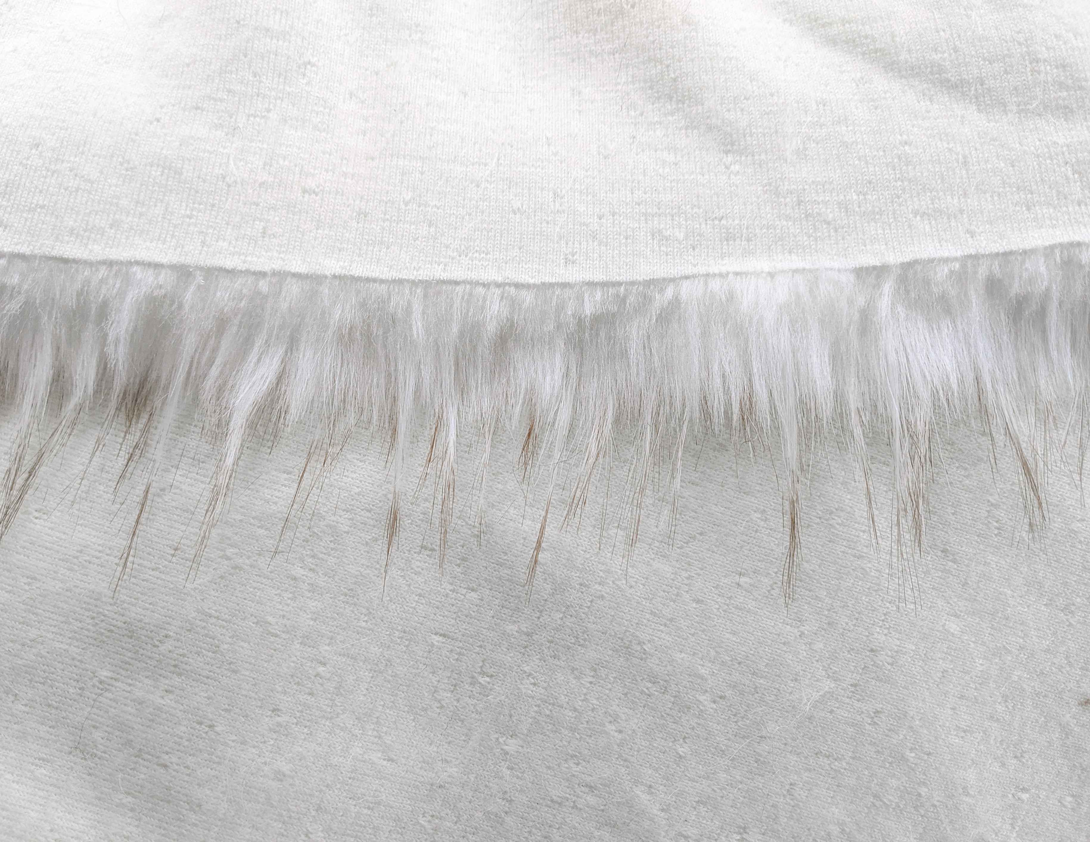 Backing of white faux fur fabric showing the long pile length of the fake fur.