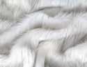 White faux fur fabric with folds.  A natural white long pile fake fur fabric.